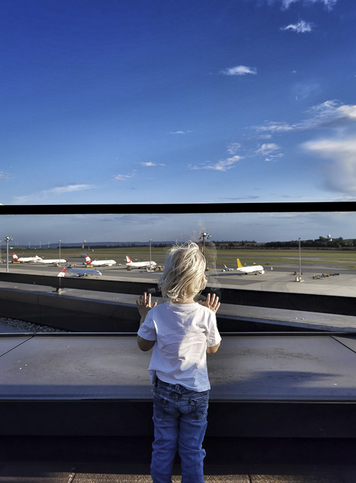 Kind bestaunt die Flugzeuge auf der Lande- und Startbahn am Flughafen Wien Schwechat